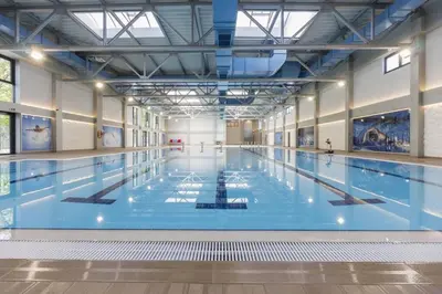 a large indoor swimming pool with blue water at Lux Apartman Crnjanski IV, Jagodina in Jagodina