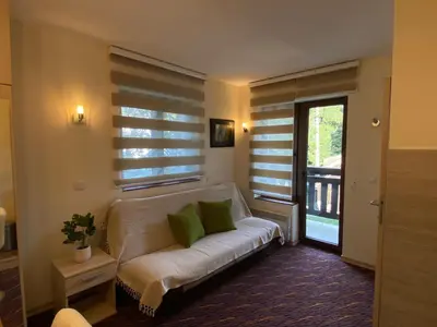 a living room with a white couch with green pillows at Apartman Zvončica 29 in Kopaonik