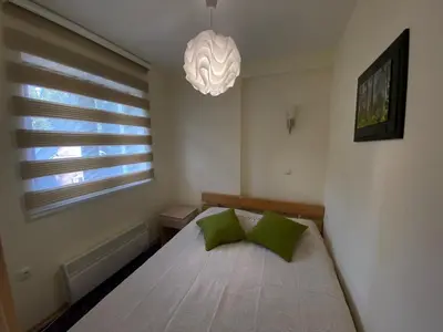 a bedroom with a bed with green pillows and a chandelier at Apartman Zvončica 29 in Kopaonik
