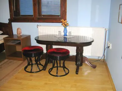 a table with four chairs and a table with a vase at Amfora Rooms Caribrod in Dimitrovgrad