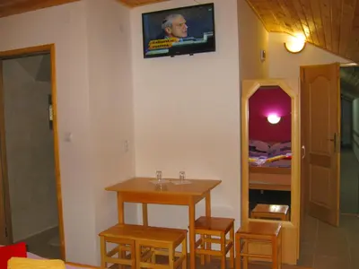 a room with a table and a tv on the wall at Amfora Rooms Caribrod in Dimitrovgrad