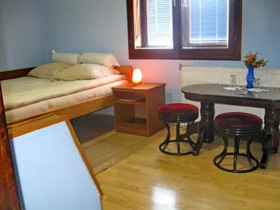 a room with a bed and a table and stools at Amfora Rooms Caribrod in Dimitrovgrad