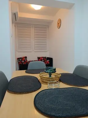 a table with chairs and a clock on the wall at Apartman 019 in Zaječar
