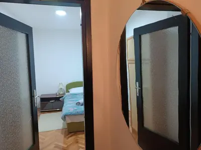 a mirror in front of a room with a bed at Apartman 019 in Zaječar