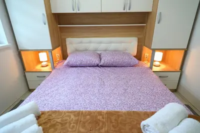 a large bed in a small room with two lamps at SokoPan in Soko Banja