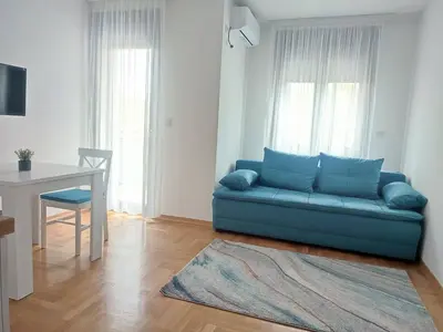a living room with a blue couch and a table at Apartman S16 Vrnjačka Banja in Vrnjačka Banja