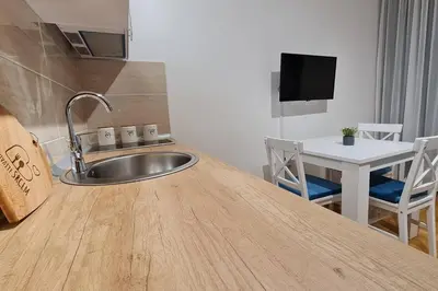 a kitchen with a sink and a table with chairs at Apartman S16 Vrnjačka Banja in Vrnjačka Banja