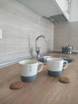 two coffee mugs sitting on a kitchen counter with cookies at Apartman S16 Vrnjačka Banja in Vrnjačka Banja
