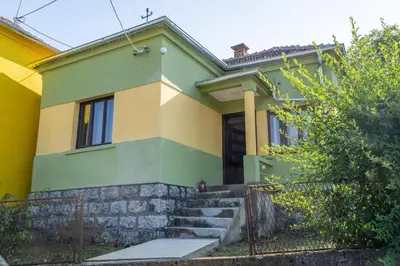 a green and yellow house with a fence at Mir i planina in Bučje