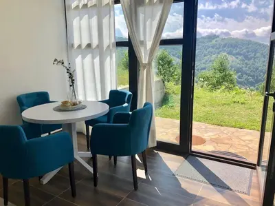 a room with a table and chairs and a window at Cozy Mountain View Apartment in Kopaonik