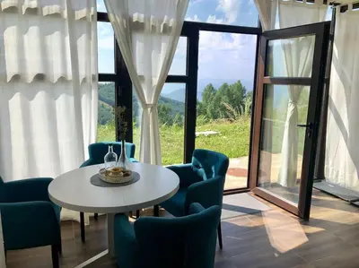 a room with a table and chairs and a large window at Cozy Mountain View Apartment in Kopaonik