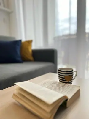 a coffee cup sitting on top of a book on a table at Apartman Sita in Vrnjačka Banja