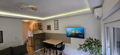 a living room with a table and a television on the wall at Apartman Sen's in Leskovac