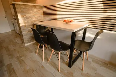 a table and chairs in a room with a wall at Apartman Sen's in Leskovac