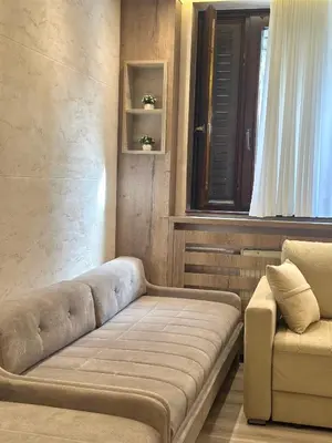 a couch and a chair in a room with a window at MB Apartmani Kopaonik in Kopaonik