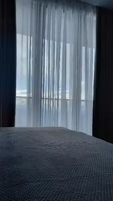 a bedroom with a bed and a window with white curtains at Apartman MK Kopaonik in Kopaonik