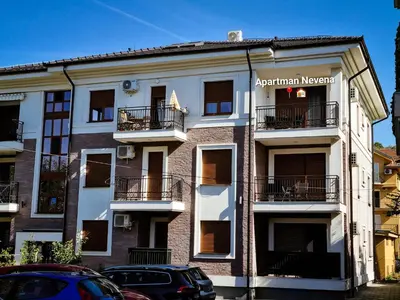 an apartment building with cars parked in front of it at Apartman Nevena in Vrnjačka Banja