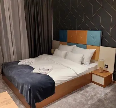 a large bed with white sheets and a wooden headboard at Lukić Apartmani in Kopaonik