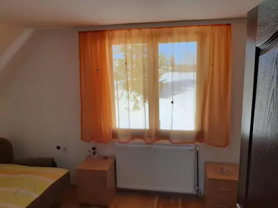 a bedroom with a window with an orange curtain at Vikend kuća Vukašinović in Kopaonik