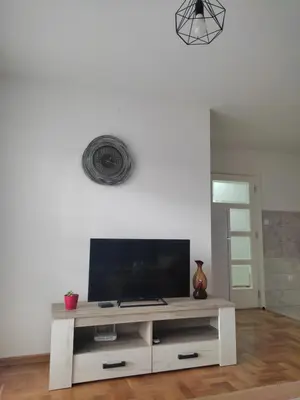 a living room with a tv on a white wall at Apartman Petra in Niš