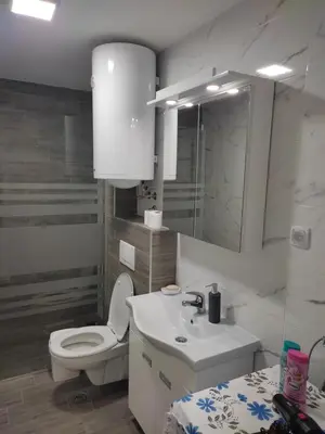 a white bathroom with a toilet and a sink at Apartman Petra in Niš
