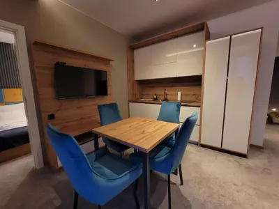 a dining room with a wooden table and blue chairs at Three Pearls in Kopaonik