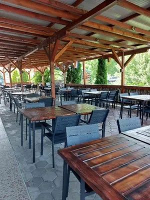 a row of wooden tables and chairs under a pavilion at Sokoterme Hotel in Soko Banja