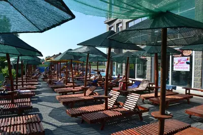 a row of benches with umbrellas on a sidewalk at Sokoterme Hotel in Soko Banja