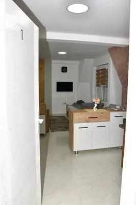 a room with a kitchen with white cabinets and a television at Grof apartmani in Zaječar