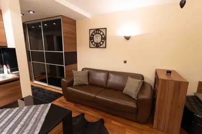 a living room with a couch and a clock on the wall at Apartman W Residence in Kopaonik