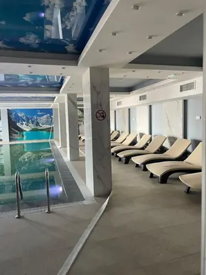 a building with a swimming pool and lounge chairs at President Kop Fibi in Kopaonik