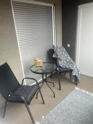 a patio with two chairs and a table and a window at Miss apartman in Jagodina