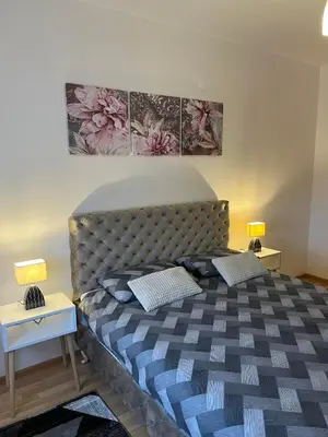 a bedroom with a large bed with two night stands at Miss apartman in Jagodina
