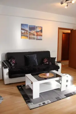 a living room with a black couch and a white coffee table at Miss apartman in Jagodina