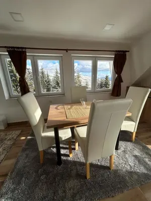 a dining room with a wooden table and white chairs at Vila Kruna Sunčani Breg in Kopaonik