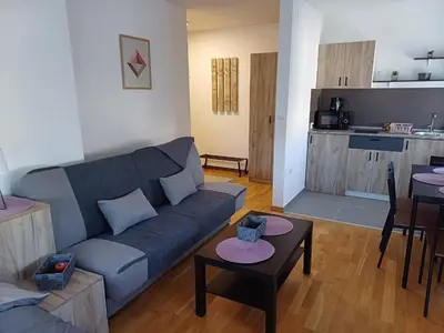a living room with a blue couch and a kitchen at Apartman NALE in Vrnjačka Banja