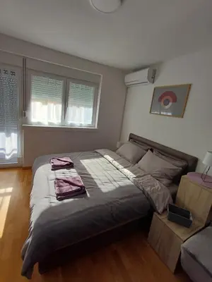 a bedroom with a large bed and a couch at Apartman NALE in Vrnjačka Banja