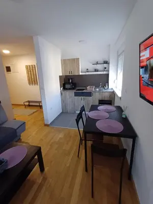 a living room with a table and chairs and a kitchen at Apartman NALE in Vrnjačka Banja