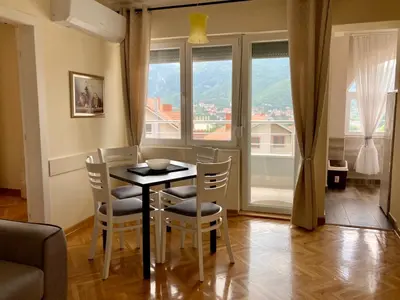a dining room with a table and chairs and windows at Apartman Ivanka in Soko Banja