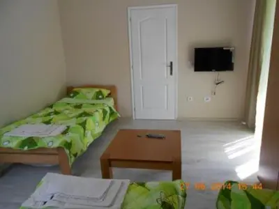 a room with two beds and a table and a tv at Guest House Konak Iris in Predejane