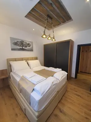 a bedroom with a large bed with white sheets at MASSIV Kopaonik centar lux apartmani in Kopaonik
