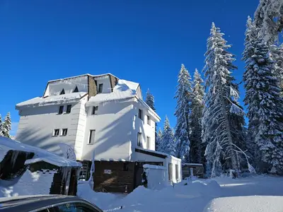 a building covered in snow next to some trees at MASSIV Kopaonik centar lux apartmani in Kopaonik