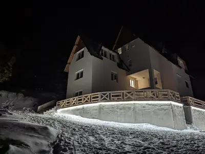 a building at night with snow in front of it at Studio Čuvarkuća in Kopaonik