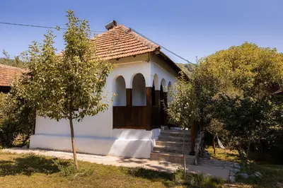 a small white house with a door and trees at Sentina kuća in Vrtovac