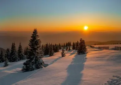 a sunset on top of a snow covered mountain with trees at Apartment Župa 111 - Župa, Kopaonik in Kopaonik
