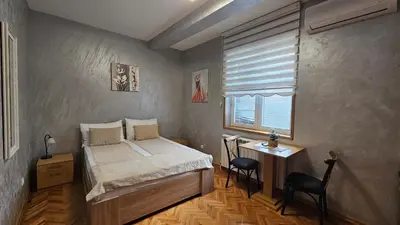 a bedroom with a bed and a table and a window at Dukat Apartmani-Studio in Vrnjačka Banja