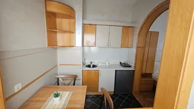 a small kitchen with wooden cabinets and a table at Dukat Apartmani-Studio in Vrnjačka Banja