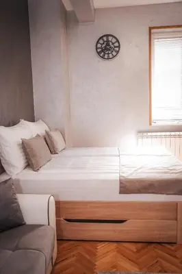 a bed in a bedroom with a clock on the wall at Dukat Apartmani-Studio in Vrnjačka Banja