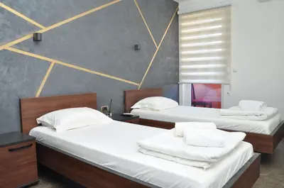 two beds in a room with white sheets at Nego apartmani in Kuršumlija