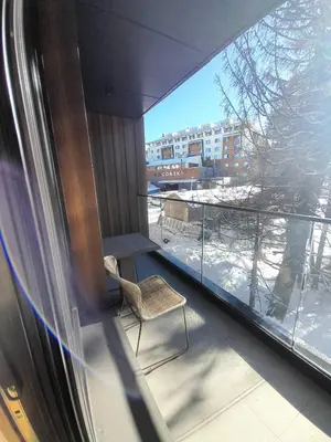 a balcony with a chair and a view of a building at Woodside RENT Kopaonik in Kopaonik